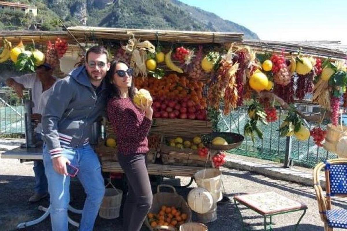 un uomo e una donna in piedi davanti a una bancarella di frutta