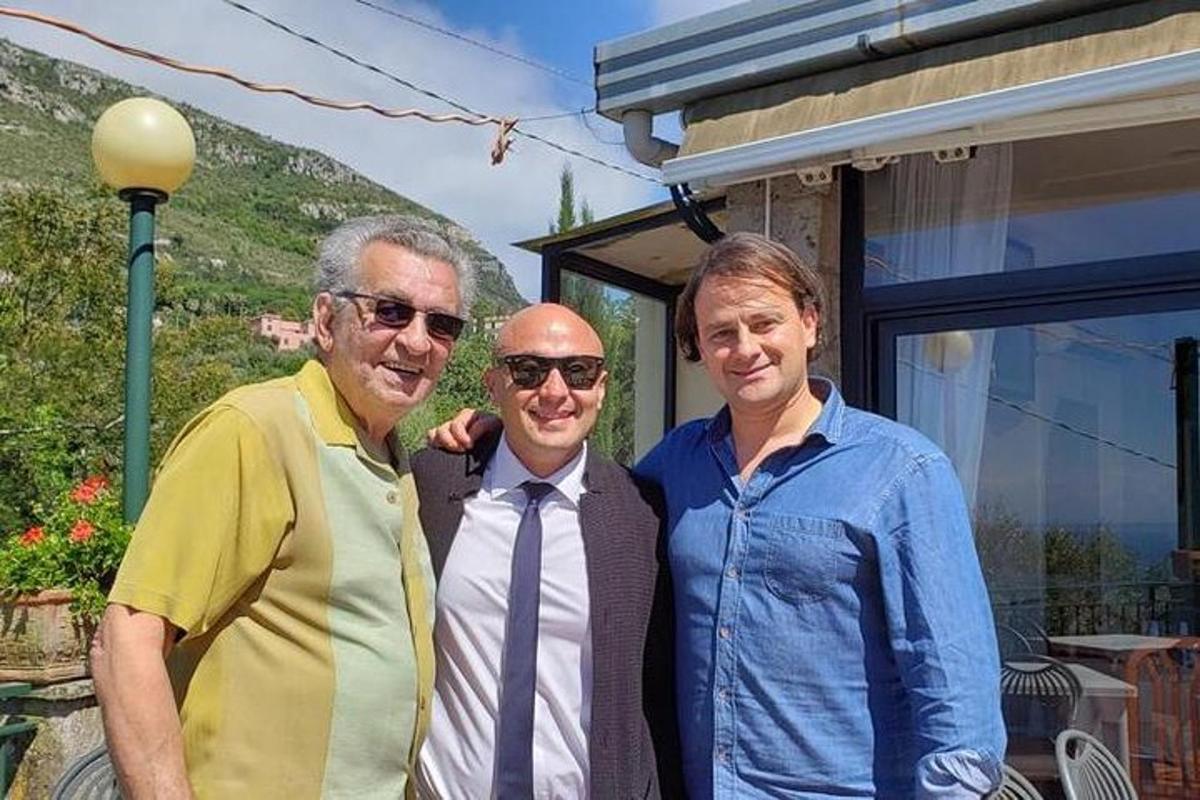 tre uomini posano per una foto davanti a una casa