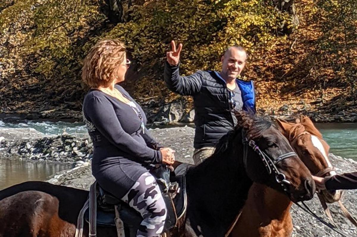 un bărbat și o femeie călare pe un cal în apă