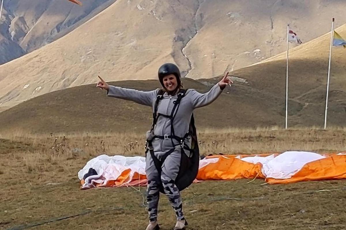 maður stendur á fjallstindi með hendurnar uppi