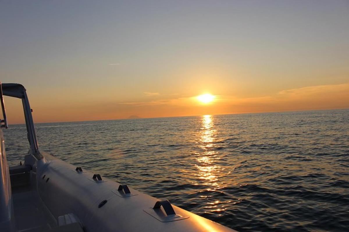 a boat in the ocean with the sun setting