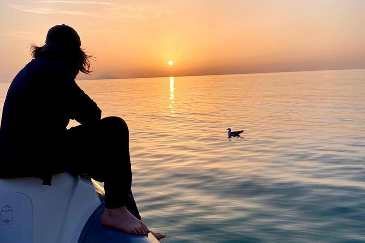 a person sitting on a surfboard watching the sunset