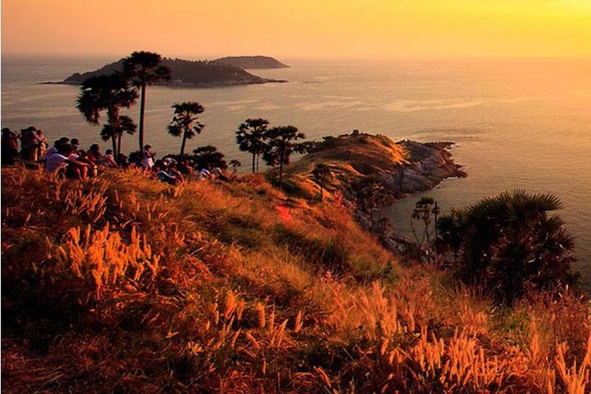 a group of people sitting on a hill overlooking the ocean