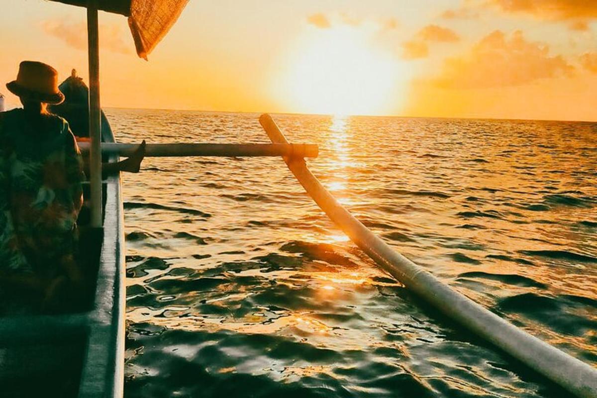 a man on a boat in the ocean at sunset