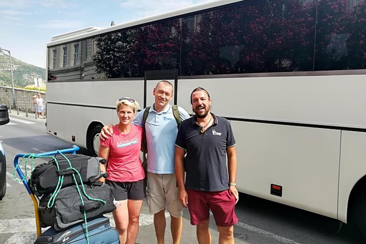 un grup de tres persones dretes davant d'un autobús