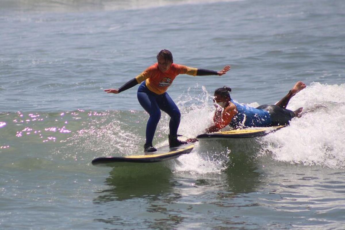 duas pessoas pegando uma onda em pranchas de surfe na água