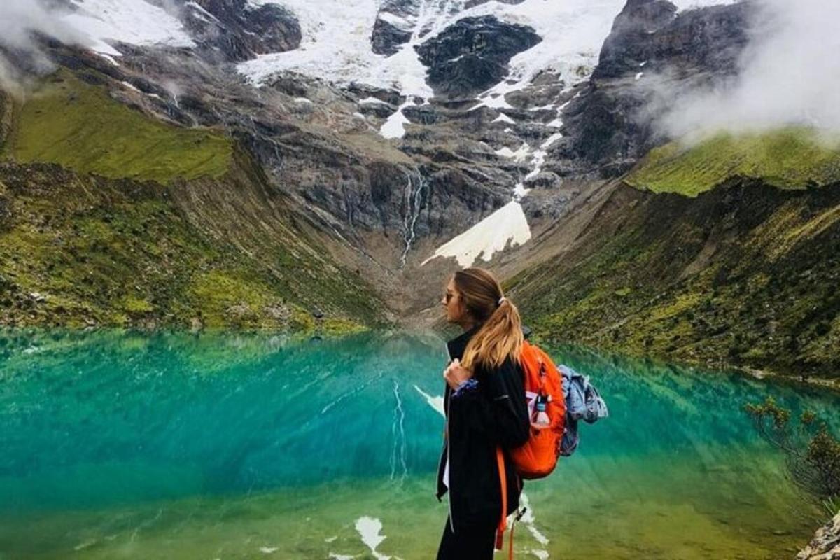 eine Frau mit einem Rucksack steht vor einem See
