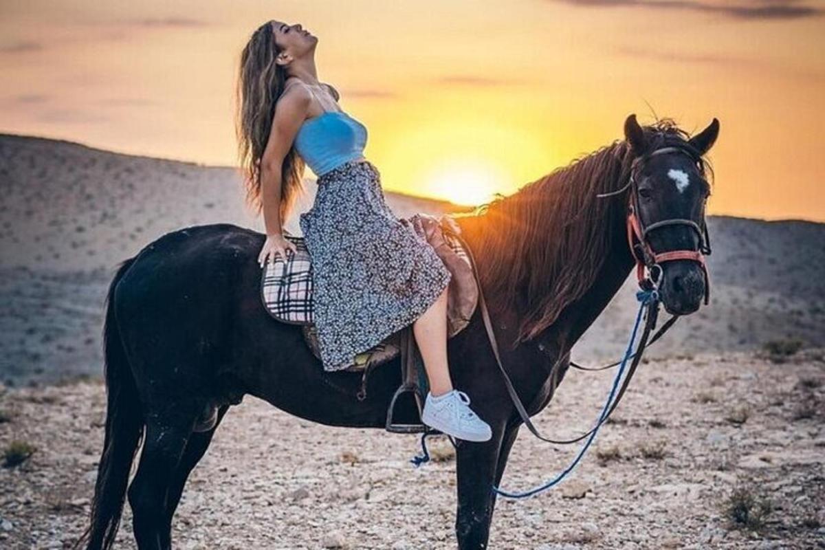 egy nő lovon lovagol a sivatagban