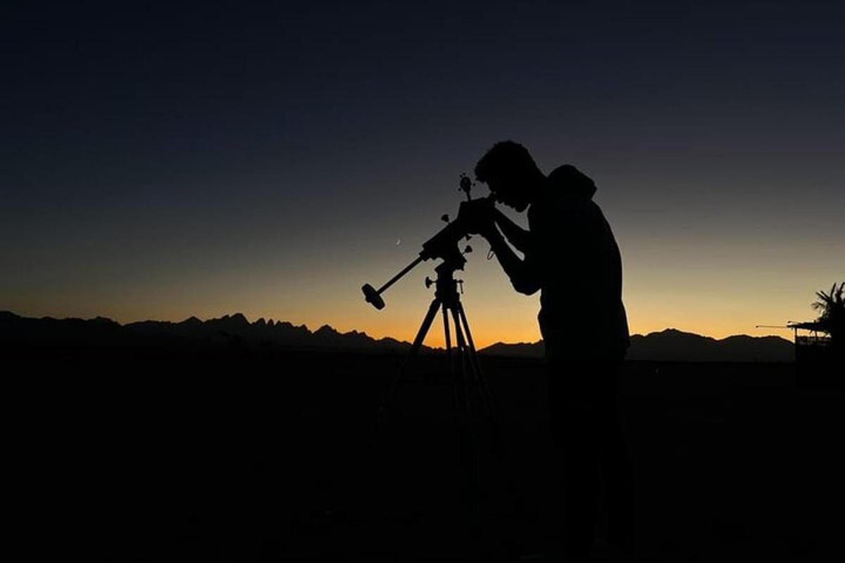 a man looking at the sky with a telescope