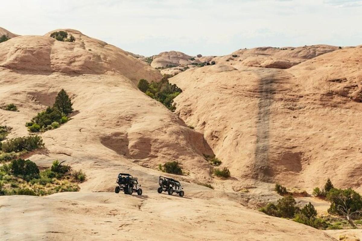 two jeeps driving down a dirt road in the desert