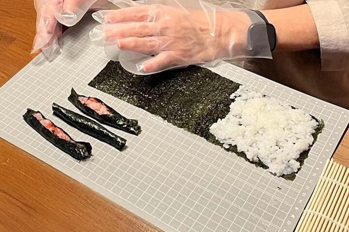seseorang sedang menyediakan sushi di atas papan pemotong