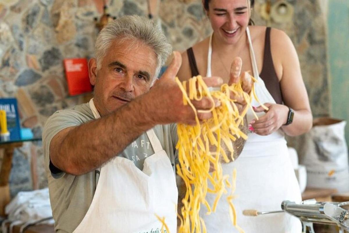 Мушкарац и жена једу шпагете у кухињи