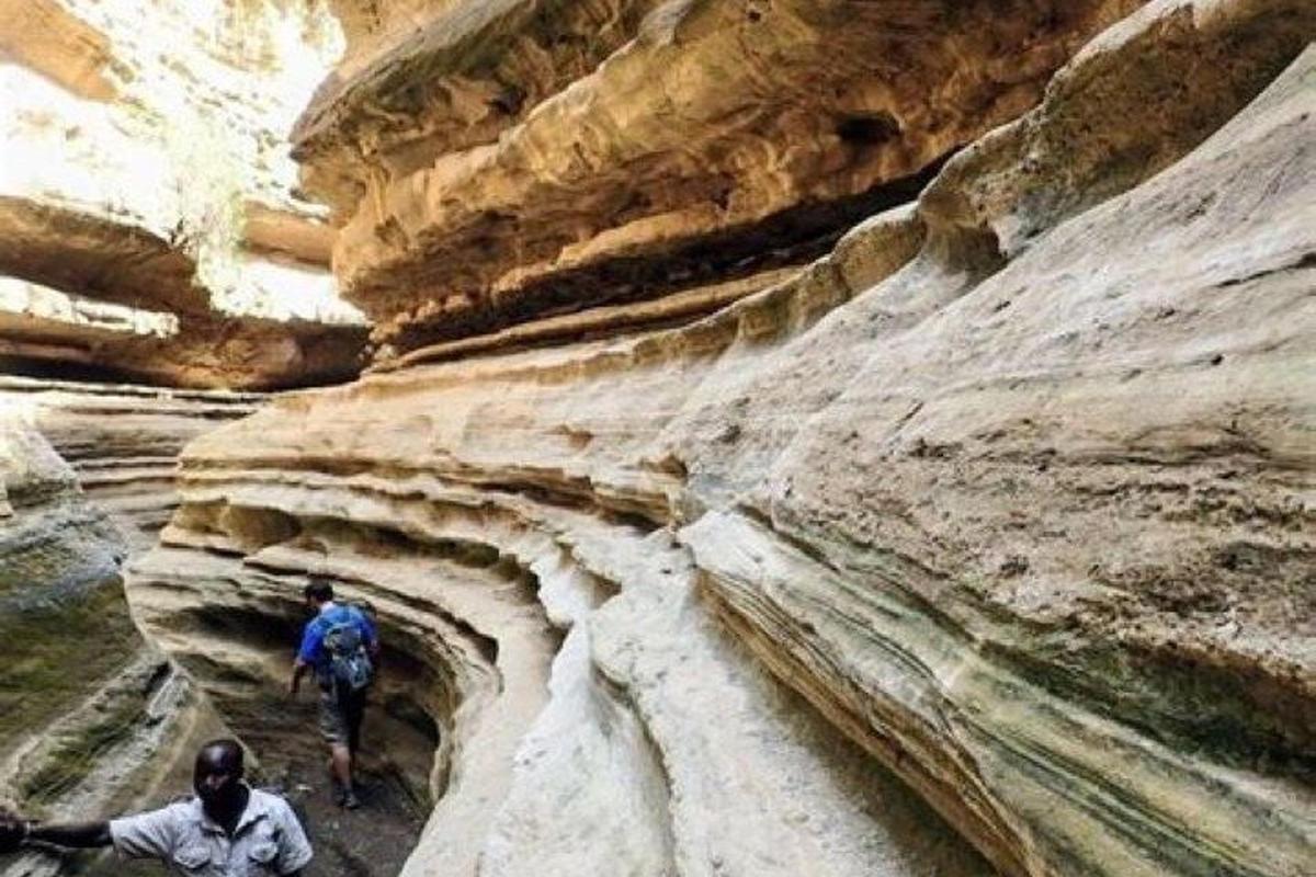 duas pessoas caminhando por um cânion com pedras