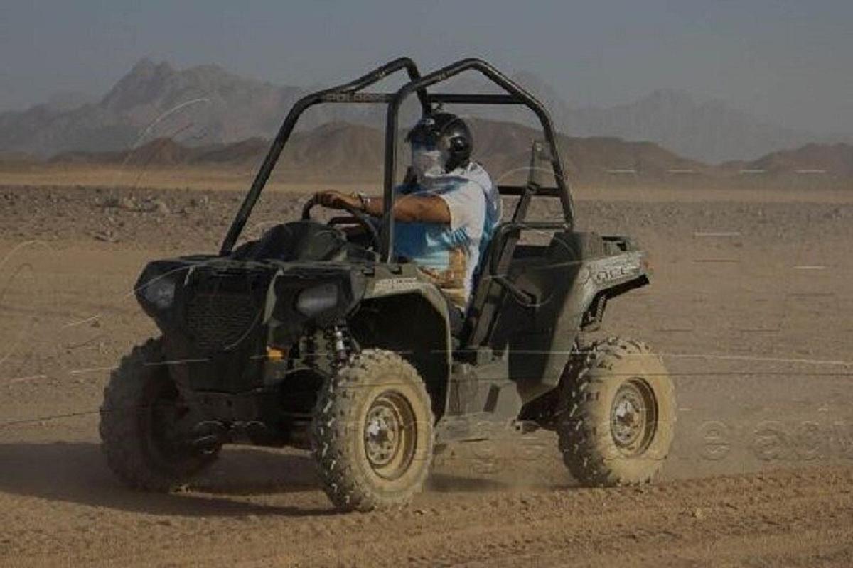 Un hombre conduciendo un vehículo con ruedas en el desierto