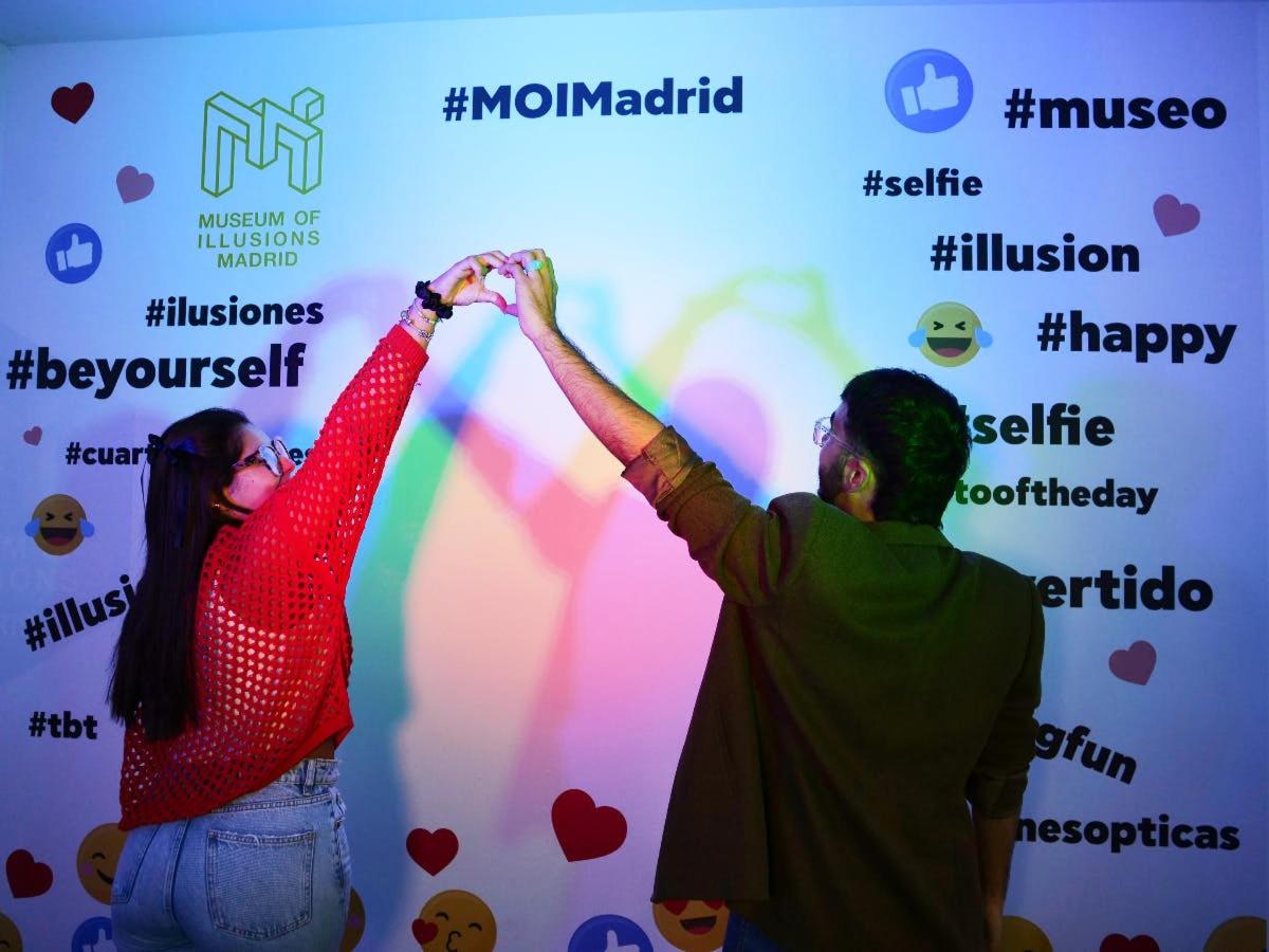 a man and a woman holding their hands up in front of a wall