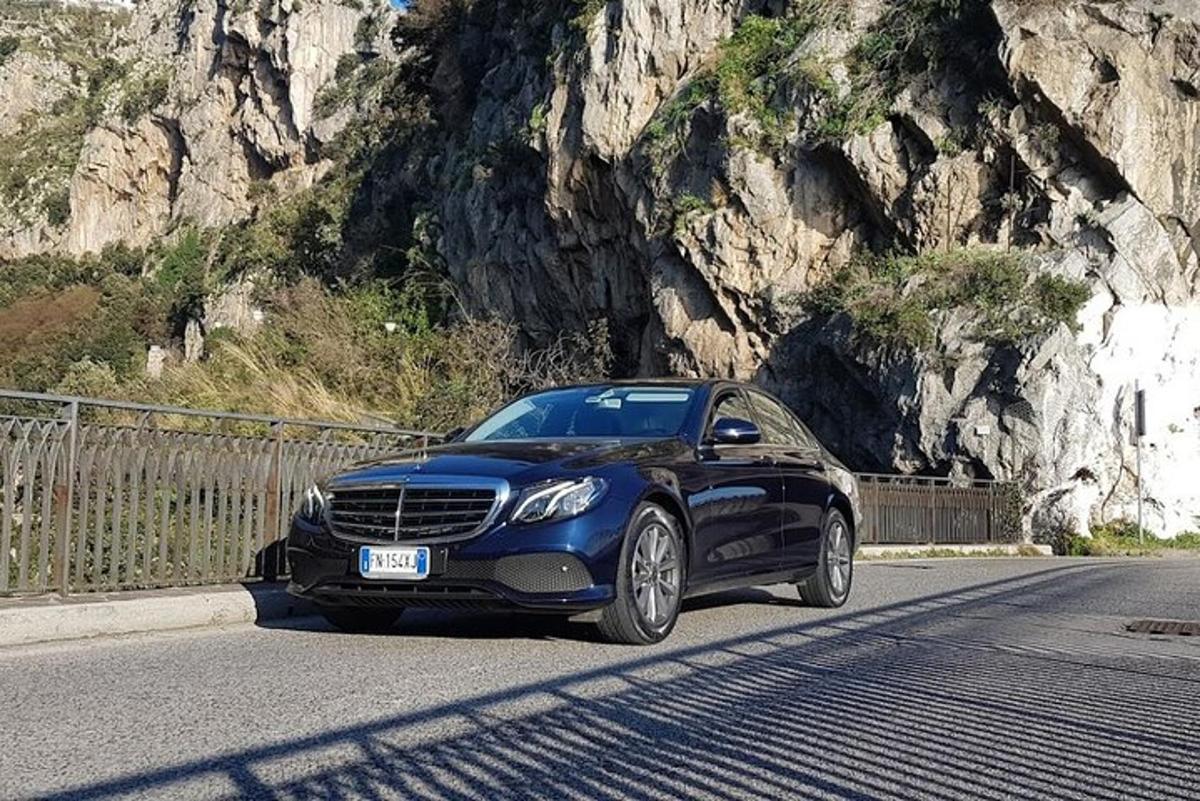 un cotxe blau circulant per una carretera a prop d'una muntanya