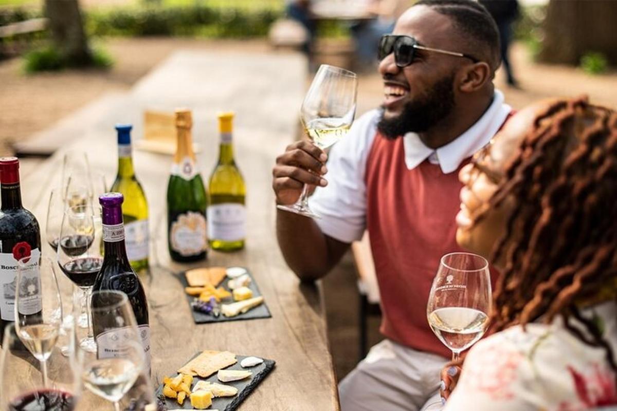 Un hombre sosteniendo una copa de vino junto a una mesa con botellas de vino.