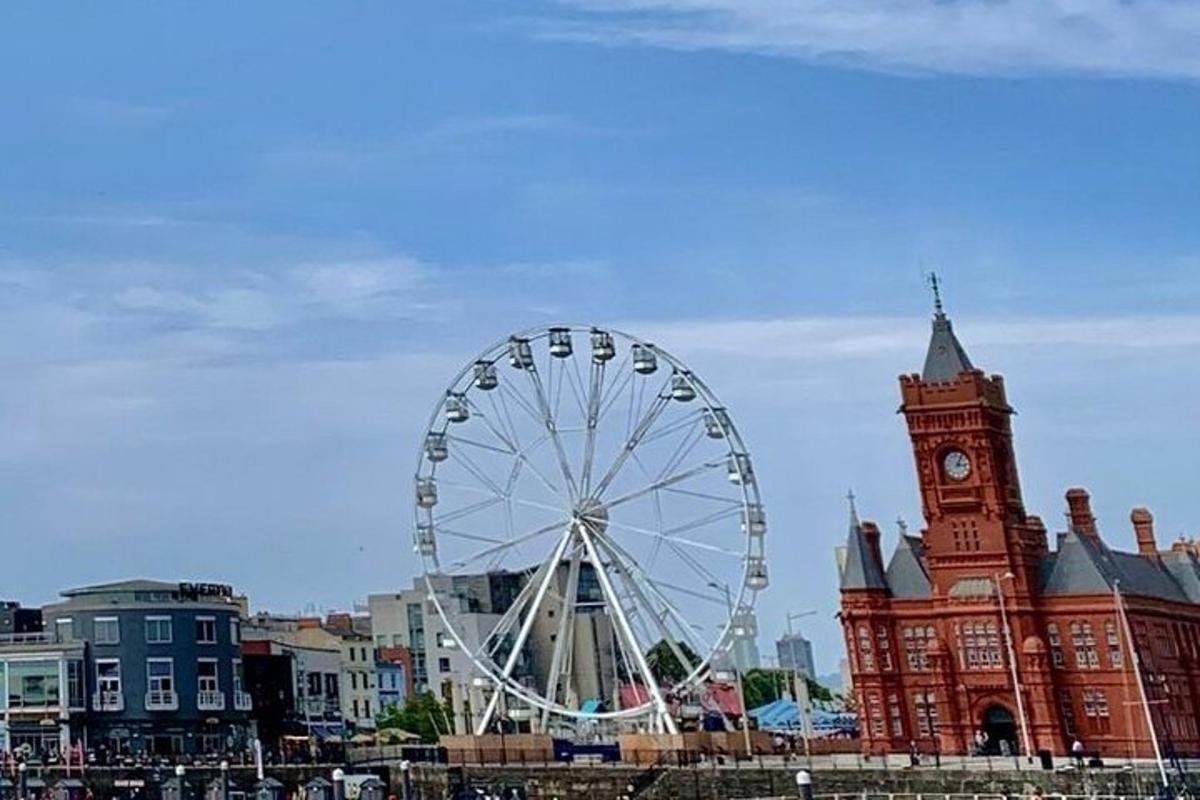 o roată panoramică în fața unei clădiri cu turn cu ceas