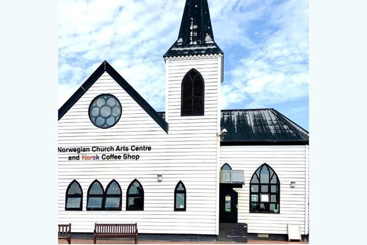 sebuah gereja putih dengan menara dan bangku di hadapan