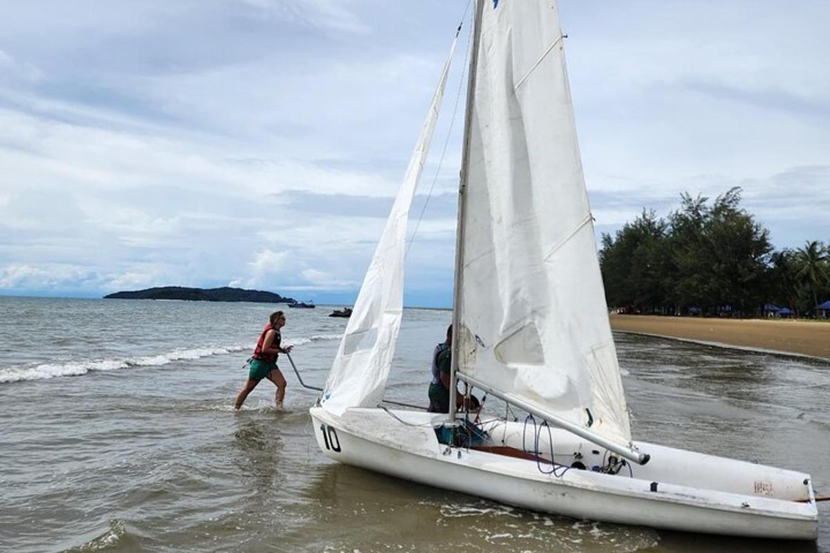 un uomo è in piedi su una barca a vela in acqua