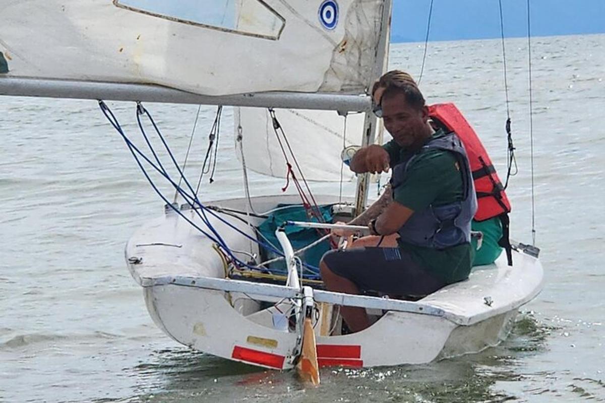 un uomo seduto su una barca a vela in acqua