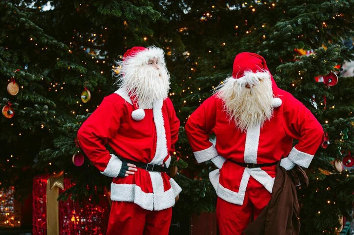 zwei Weihnachtsmänner stehen vor einem Weihnachtsbaum