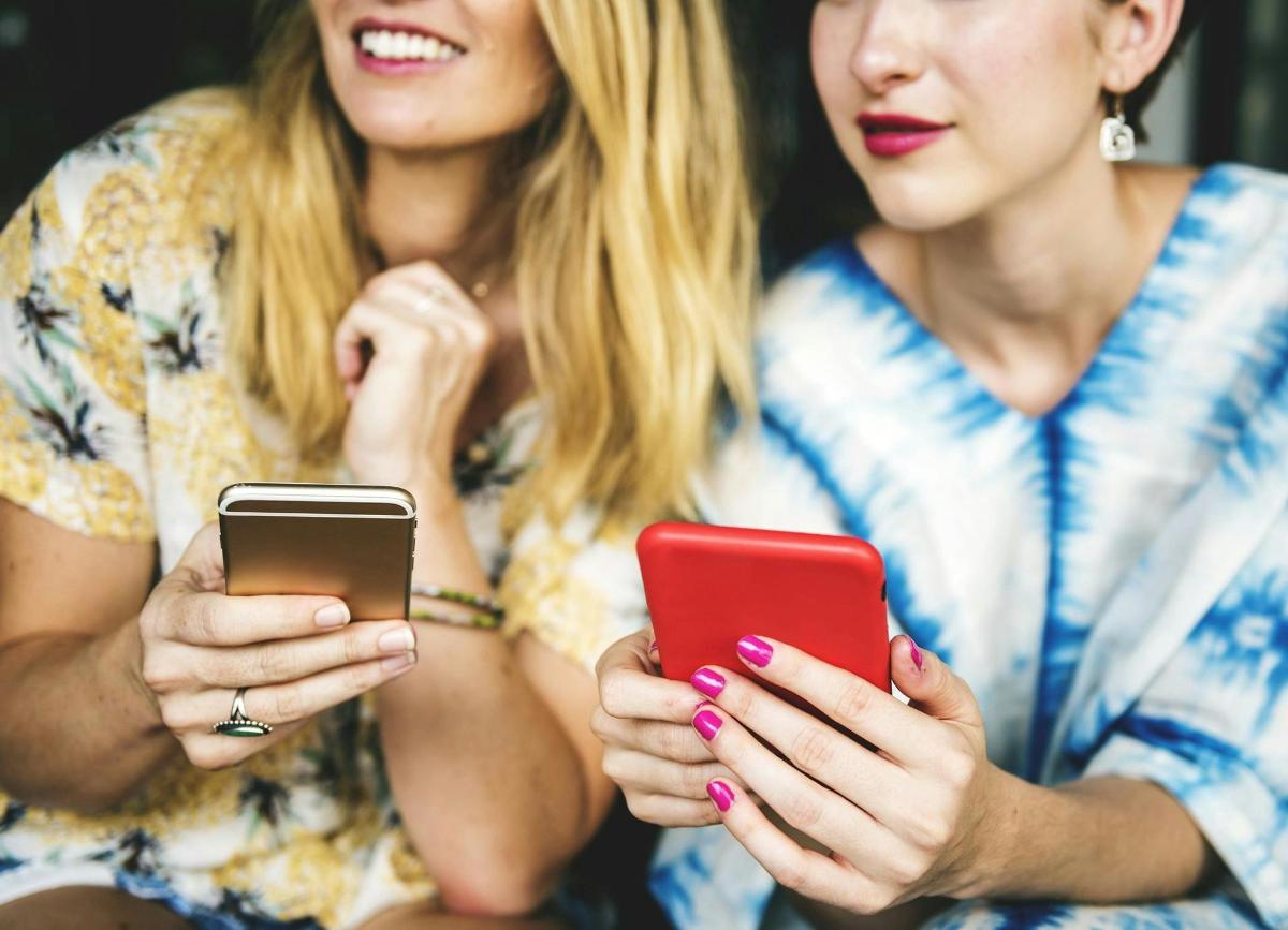 Dvě ženy se dívají do svých mobilních telefonů