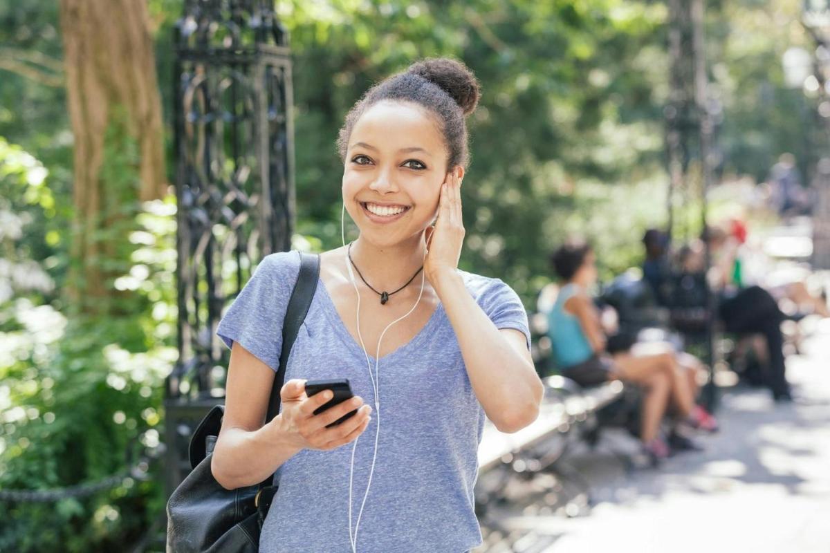 una donna che tiene in mano un cellulare e ascolta musica