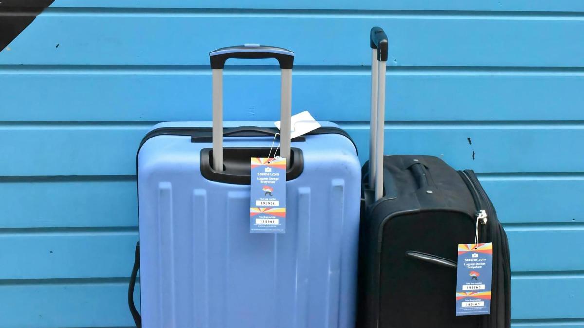 two pieces of luggage sitting next to a blue wall