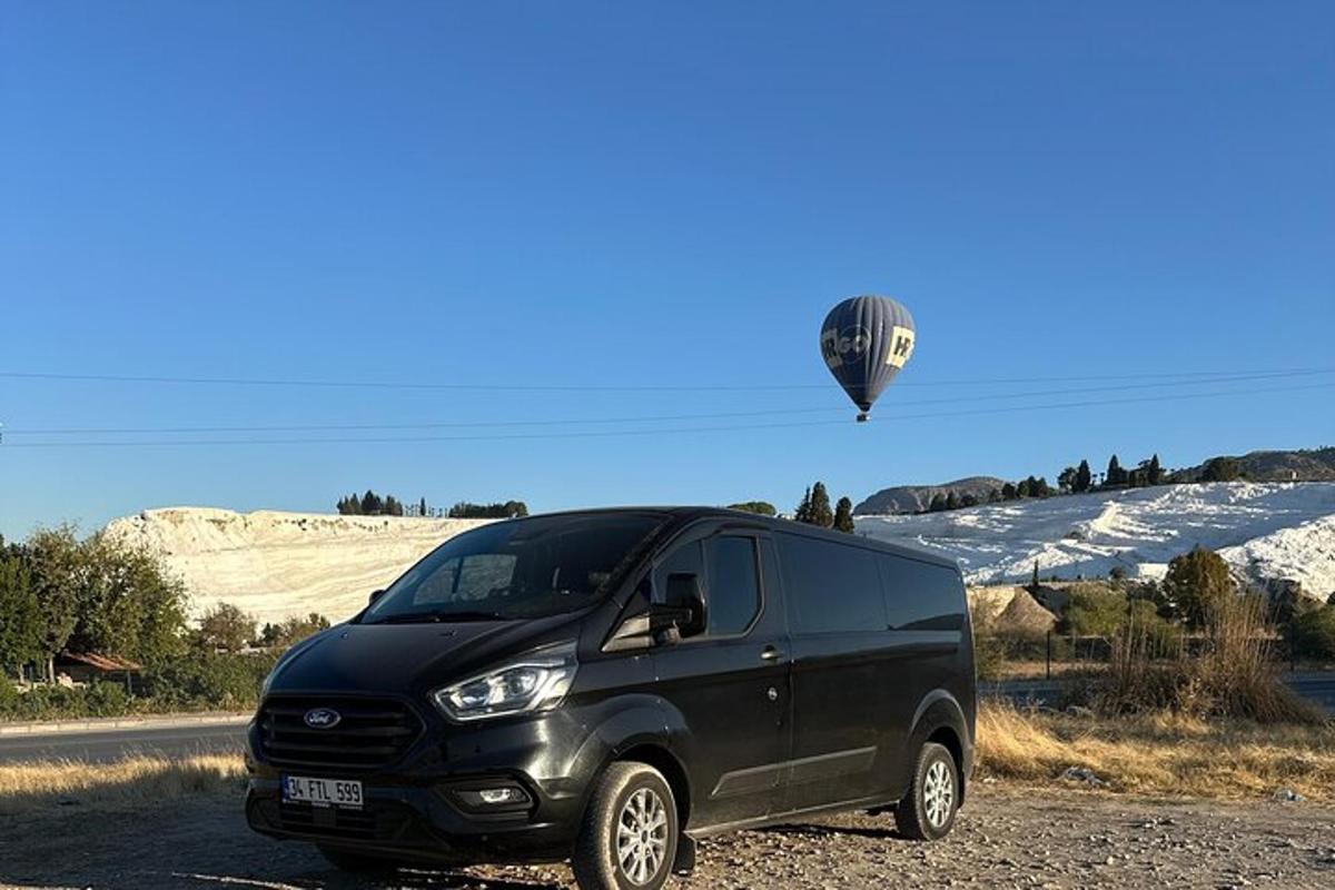un furgone nero parcheggiato sul ciglio della strada con una mongolfiera