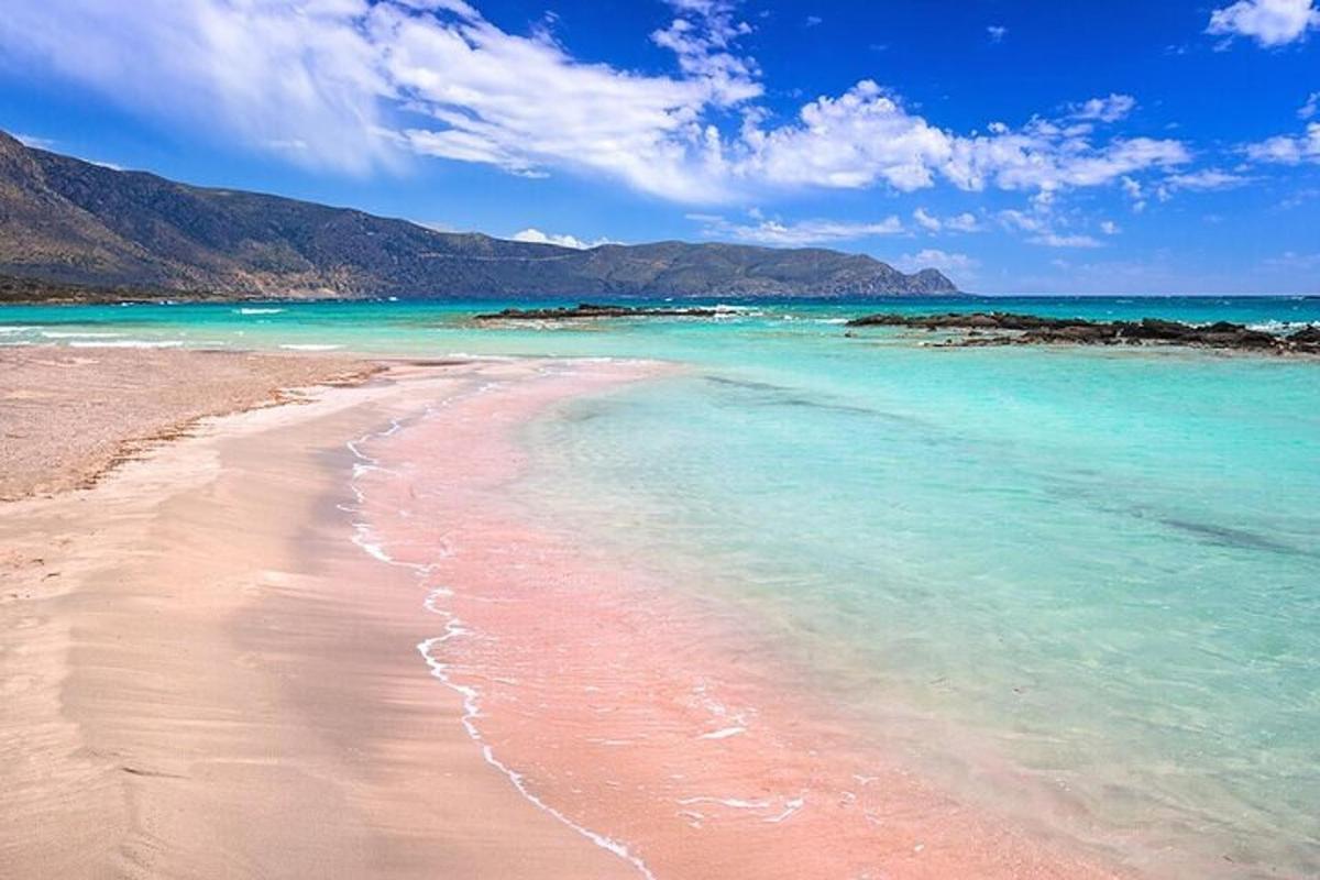 una platja amb aigües blaves i muntanyes al fons