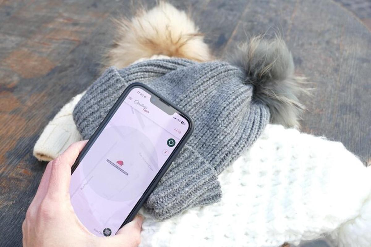 una persona che tiene in mano un cellulare con un cappello e un cane