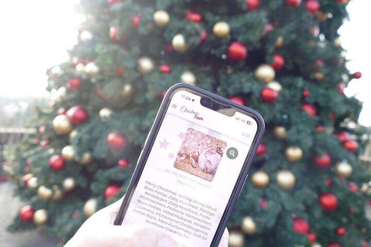 a person holding a cell phone in front of a christmas tree