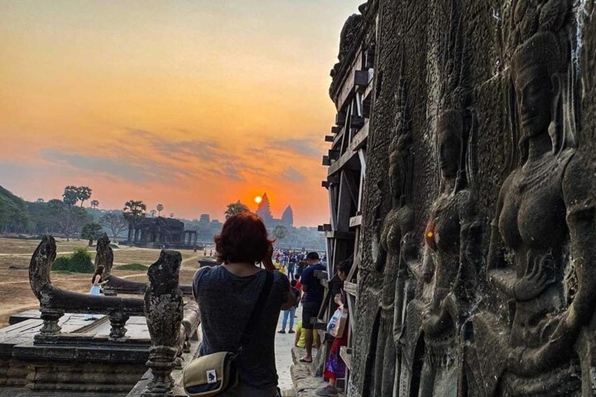 Una mujer parada junto a un edificio mirando la puesta de sol.