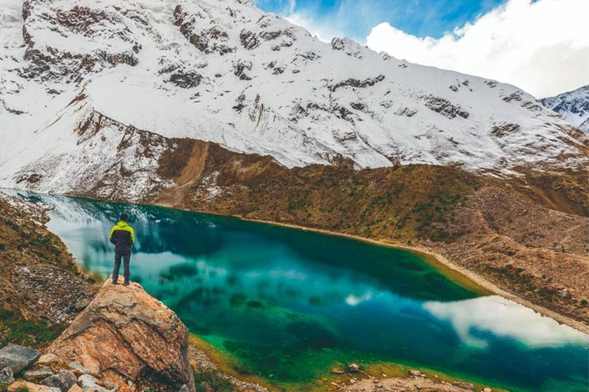 una persona in piedi sulla cima di una montagna vicino a un lago