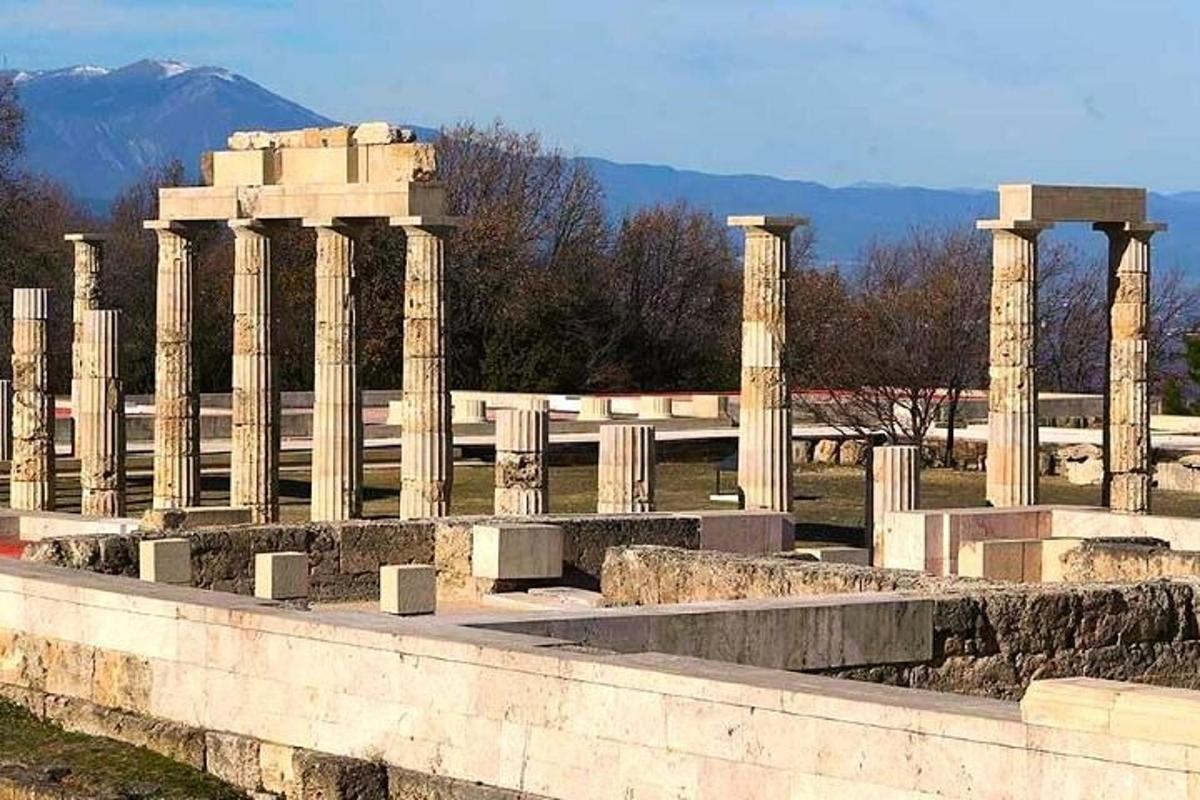 a row of columns in a cemetery with a mountain in the background