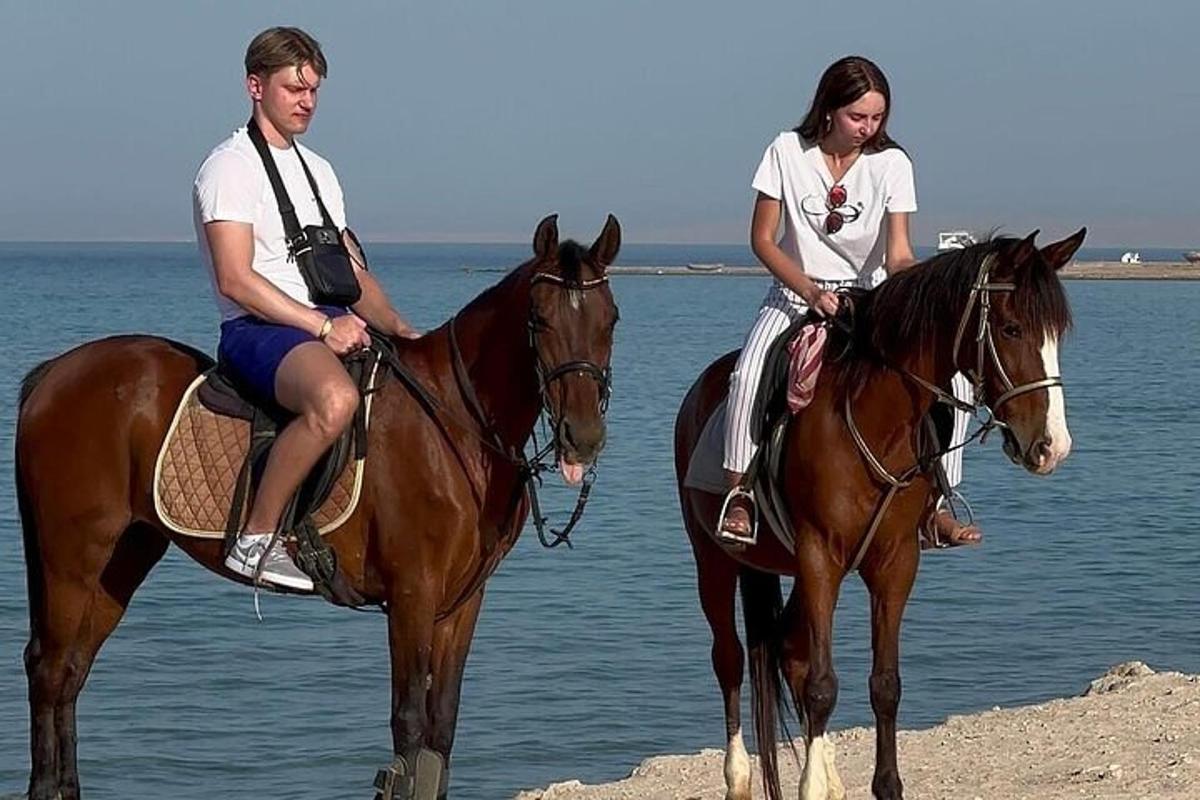 un home i una dona muntant a cavall a la platja