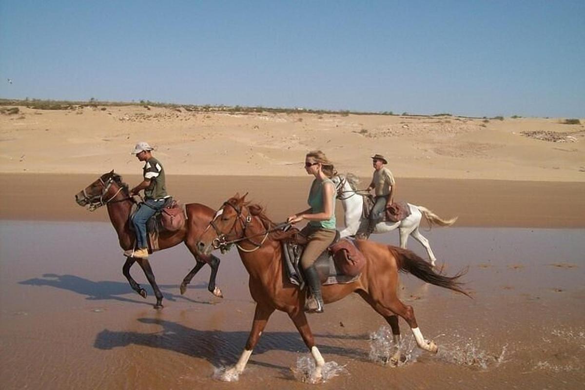 en gruppe mennesker som rir på hester på stranden