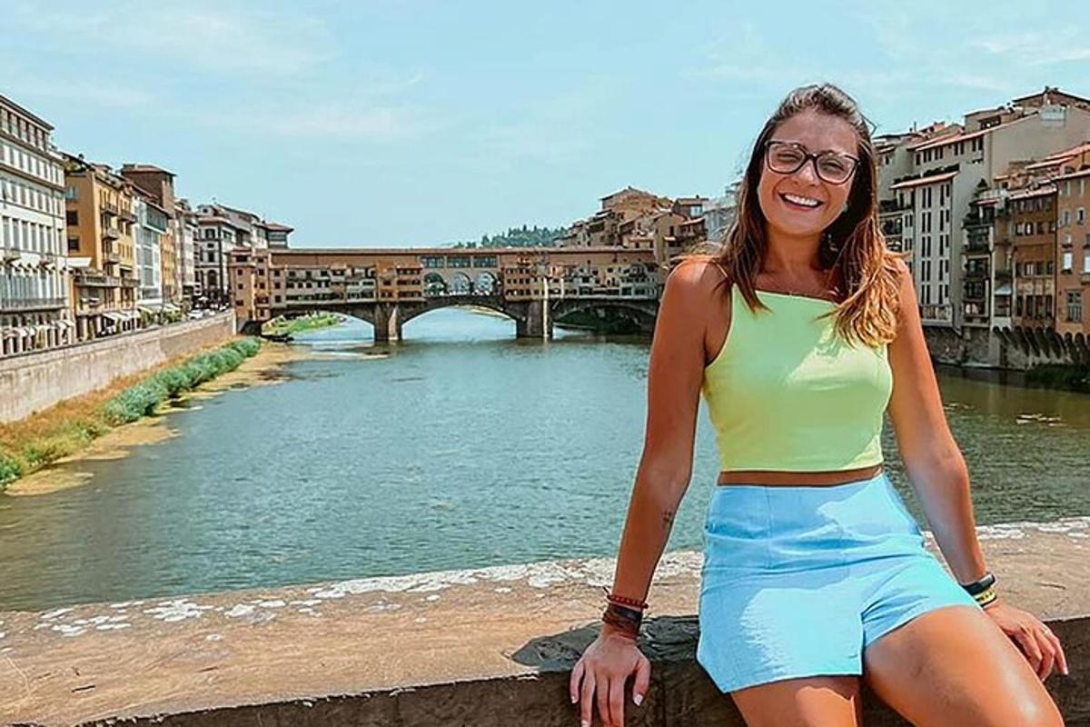 una donna seduta su un muro vicino a un fiume