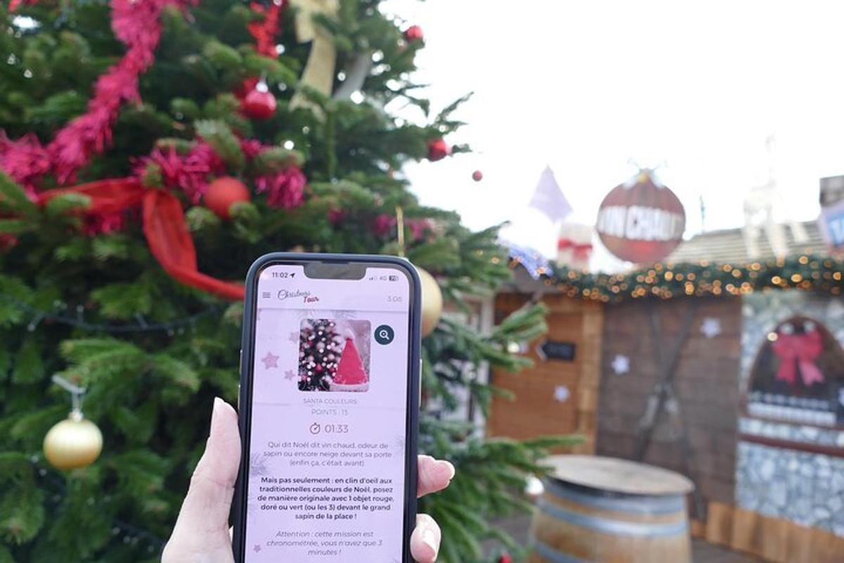 Una persona sosteniendo un teléfono celular frente a un árbol de Navidad.