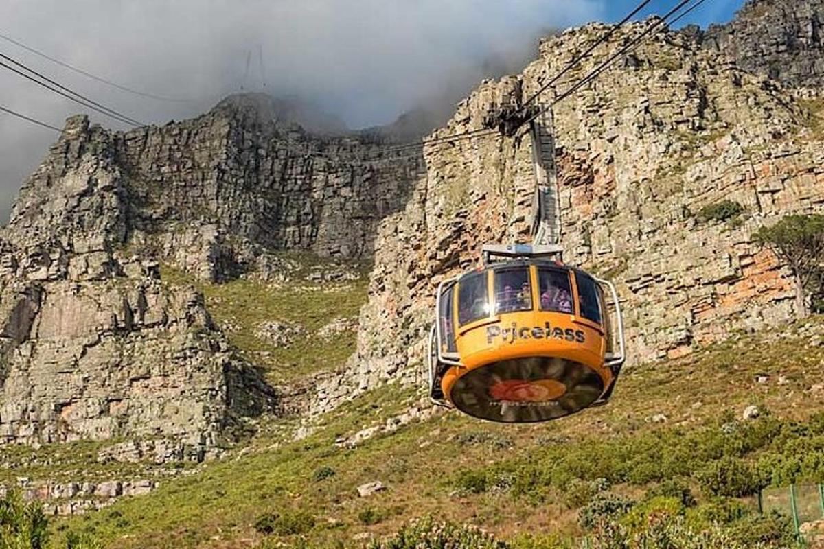 isang dilaw na tren sa isang burol na may bundok
