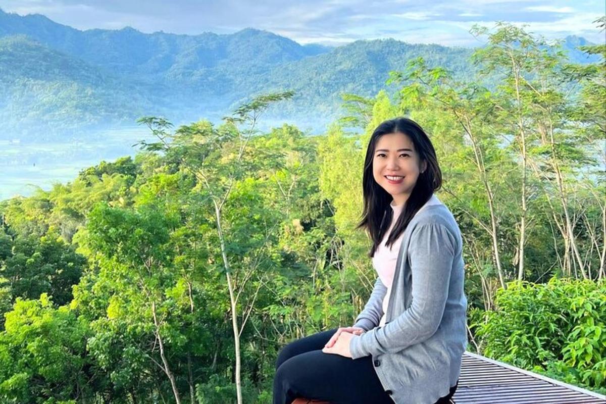 a woman sitting on top of a roof with mountains in the background
