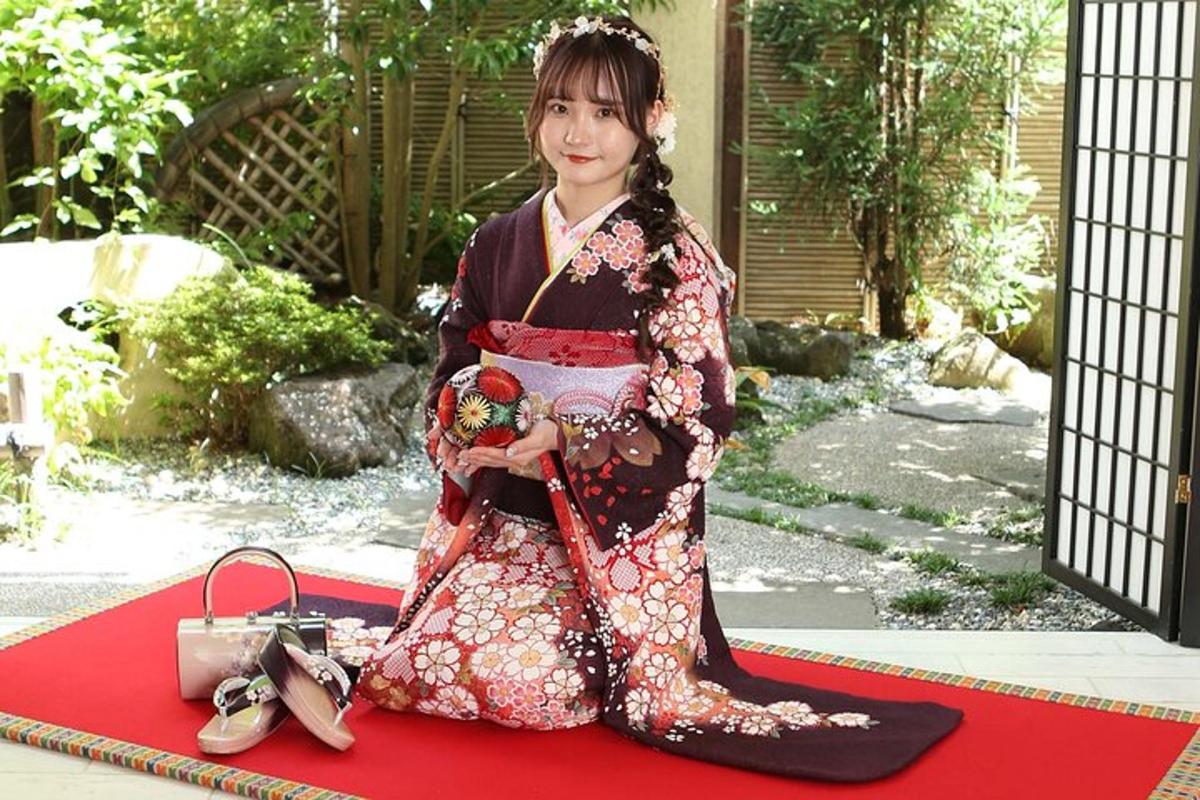 seorang gadis berkimono duduk di atas permaidani merah