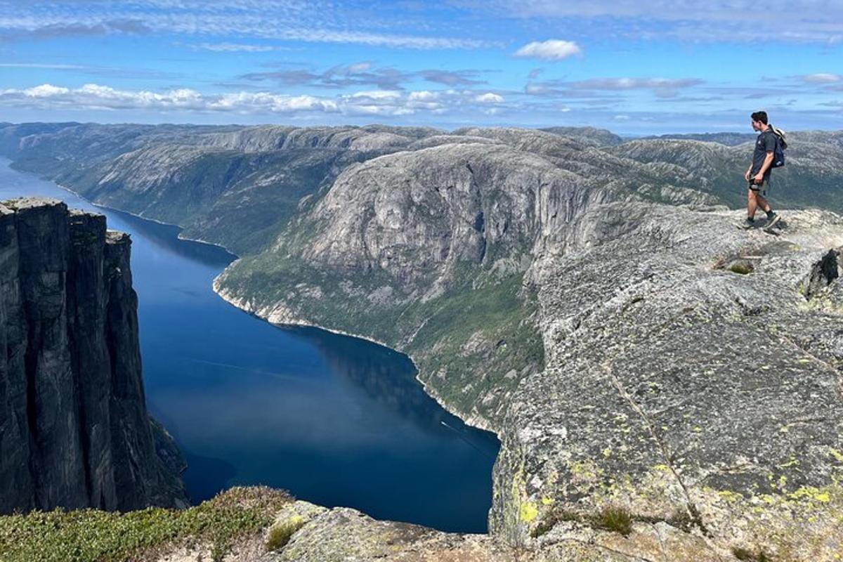 maður stendur á fjallstindi með útsýni yfir vatn