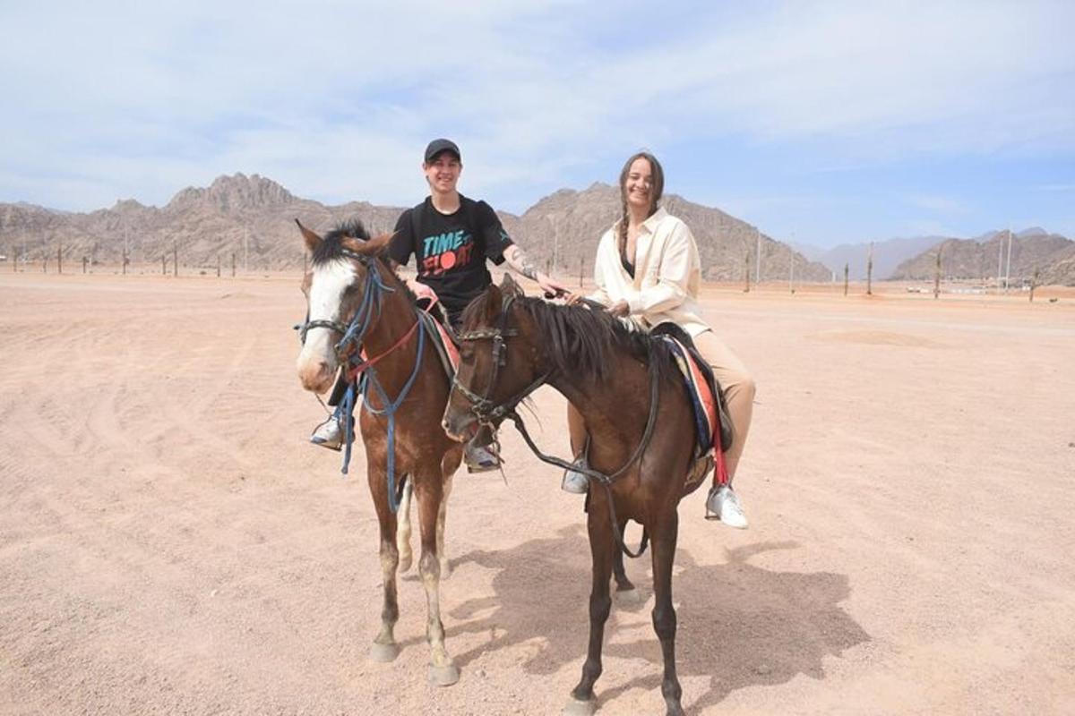 um homem e uma mulher cavalgando no deserto