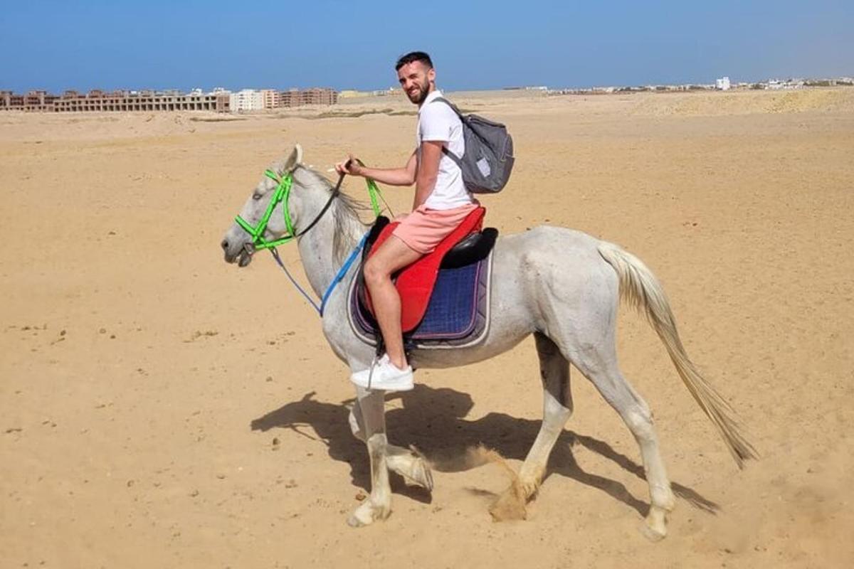 um homem cavalgando na praia