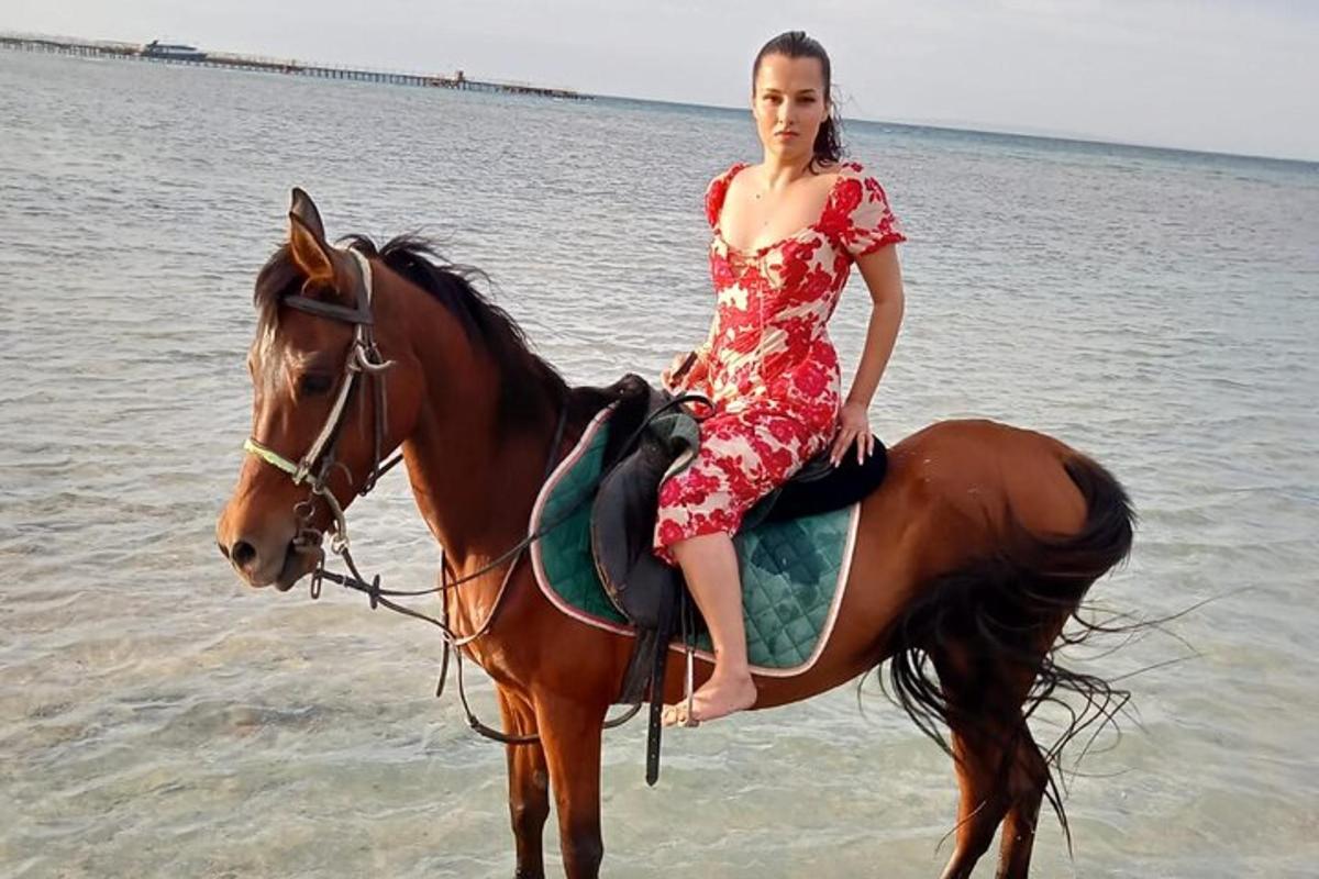 žena v šatech jedoucí na koni na pláži