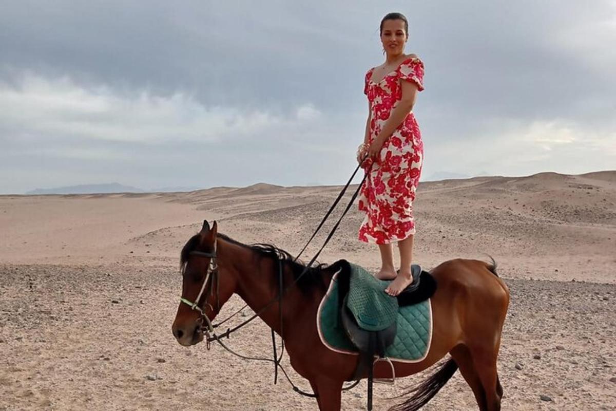 uma mulher em pé num cavalo no deserto