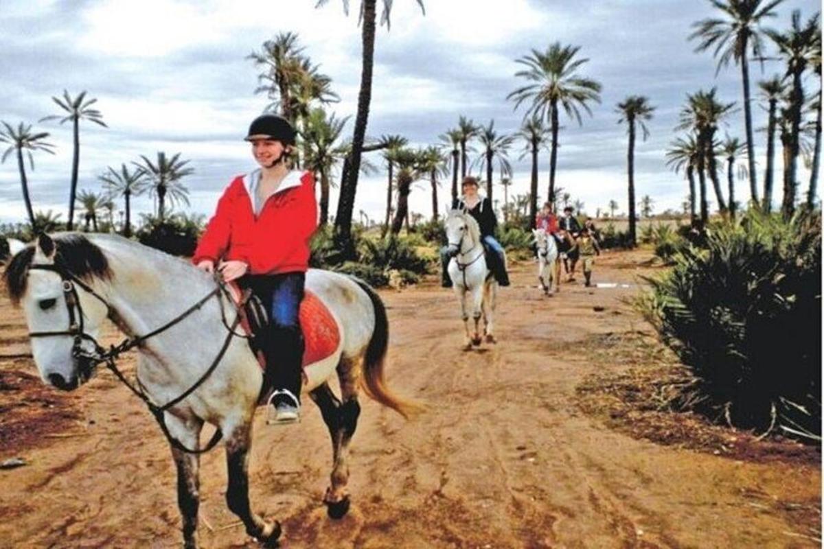 two people riding horses on a dirt road with palm trees