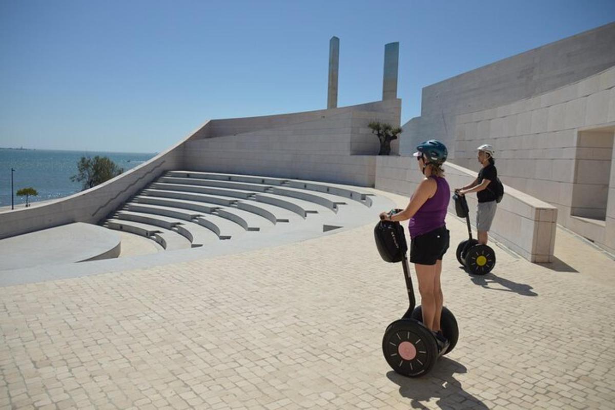Dos mujeres viajando en scooters frente a un edificio